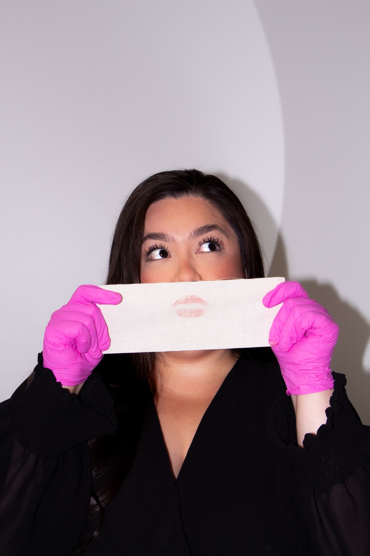 Jaquie in pink gloves holding a muslin waxing strip with a lipstick kiss mark at Eres Beauty Studio